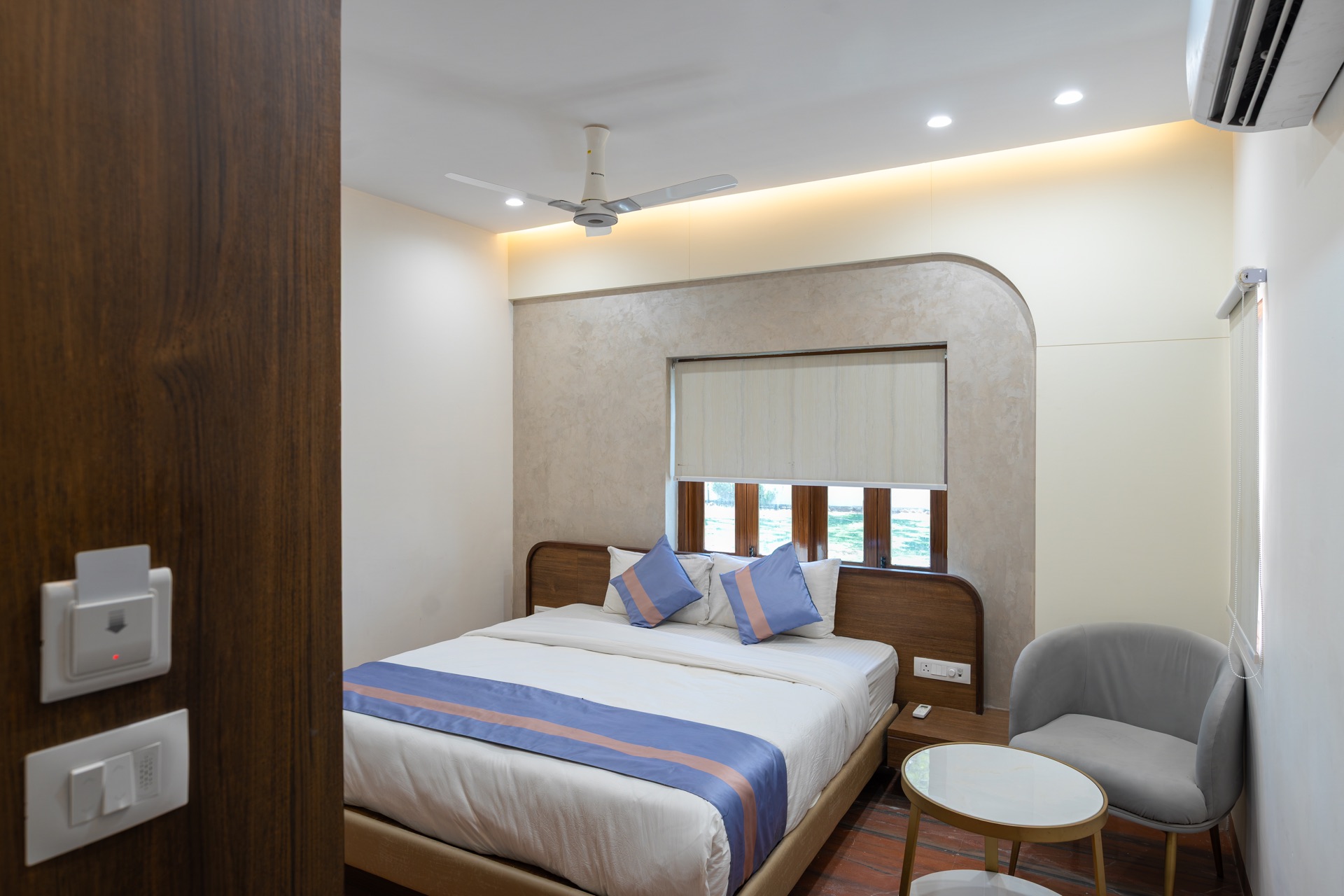 Deluxe Room at Hotel Ramdev — double bed, armchair, and a window onto the garden